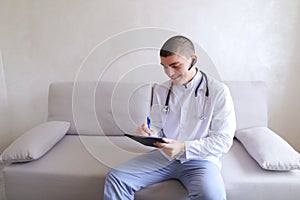 Modern male doctor talks to patient by bluetooth and writes to r