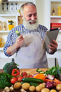Modern man looking for a recipe with the help of tablet standing