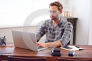 Modern man typing on a laptop while seated at desk
