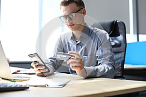 Modern man using credit card and mobile phone for online payment. Mobile shopping concept