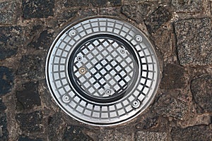 Modern manhole on the stone pavement