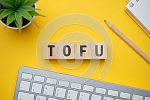 Modern marketing buzzword - TOFU Top of funne. Top view on wooden table with blocks. Top view