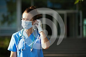 Modern medical doctor woman in scrubs outdoors near hospital