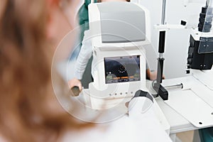 Modern medical equipment. Close up of ophthalmologist using auto refractometer while examining child eyes.