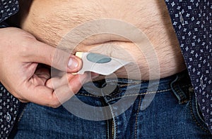 A modern medical patch for prostatitis and urinary tract infections. A man glues a urological patch on his stomach, close-up