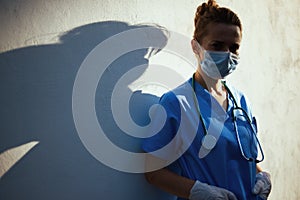 Modern medical practitioner woman outside in city near wall