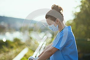 Modern medical practitioner woman in scrubs outdoors in city