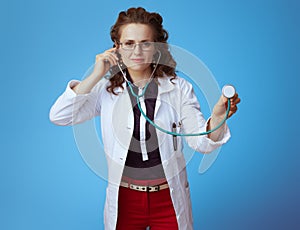 Modern medical practitioner woman using stethoscope on blue