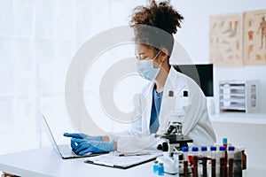 Modern medical research laboratory. African female scientist working with micro pipettes analyzing biochemical samples, advanced