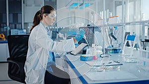 Modern Medical Research Laboratory: Female Scientist Working with Micro Pipette, Using Digital Tab