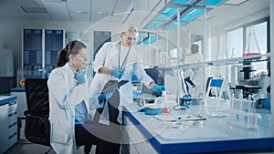 Modern Medical Research Laboratory: Two Female Scientists Working Using Digital Tablet, Analysing