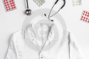 Modern medicine workplace with overall, meds and stethoscope white table flat lay space for text