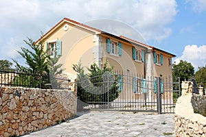 Modern Mediterranean villa with new facade and open blue wooden window blinds with traditional stone driveway in front closed with