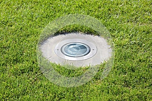 Modern metal spotlight led lamp for outdoor use of circular shape recessed in a grass area