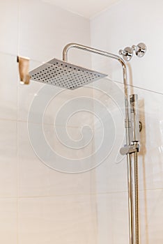 Modern metal square shower with faucet with soap and towel in expensive loft bathroom