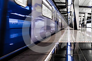 Modern metro station at night. A lonely girl is waiting for the train to arrive