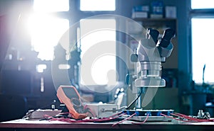 Modern microscope, connectors component and large green microcircuit in workshop laboratory
