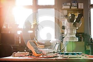 Modern microscope, connectors component and large green microcircuit in workshop laboratory
