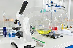 Modern microscope on the workplace near test tubes and flasks wi