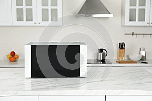 Modern microwave oven on white table in kitchen, space for text