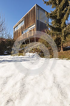 Modern minimal wooden house exterior. The season is winter and therefore you can see the snow in the garden photo