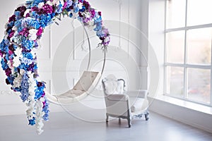 Modern minimalism interior. Flower decorated chair with leather armchair in white room with big panoramic window.