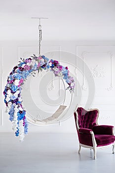 Modern minimalism interior. Flower decorated chair with violet armchair in white room.