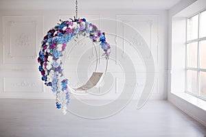Modern minimalism interior. Flower decorated ring chair in white room with big panoramic window.