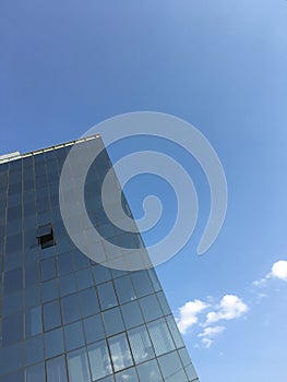 Modern minimalist architecture. Tall office building glass windows against clear blue sky business texture background