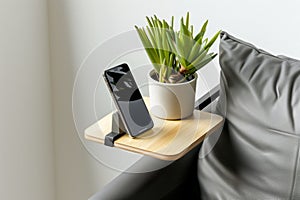 modern minimalist armrest table with a plant and a smartphone