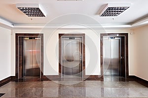 Modern minimalist business centre lobby interior with three closed steel lift doors