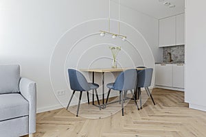 Modern minimalist kitchen and dining room interior design with wooden furniture, oak floor. blue chairs.