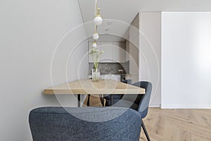 Modern minimalist kitchen and dining room interior design with wooden furniture, oak floor. blue chairs.