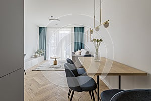 Modern minimalist kitchen and dining room interior design with wooden furniture, oak floor. blue chairs.