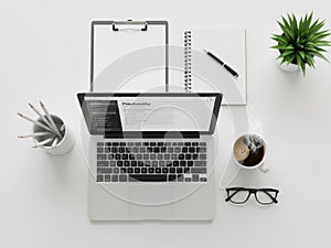 Modern minimalist office desk setup with laptop notebook glasses and plant overhead view