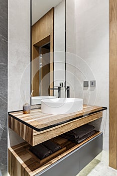 Modern minimalistic bright bathroom with white sink and wooden furniture