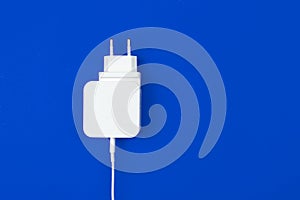 Modern mobile charger for smartphone on a blue background. Flat lay, top view, copy space