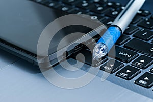 Modern mobile phone, blue ball pen on laptop
