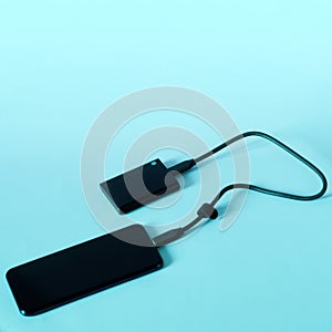 Modern mobile phone and an external portable SSD connected to it on light gradient background. Portable Solid State Drive. OTG