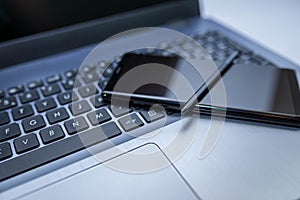 Modern mobile phone with stylus on laptop computer keyboard , shallow depth of field