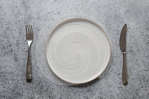 Modern modus, fork and knife on grey stone table. Minimal table place setting. Space for text or menu. View from above photo