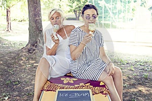 Modern mom and young daughter eating ice cream