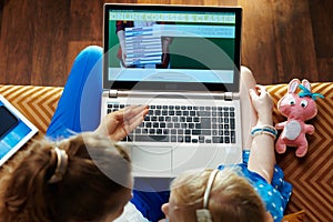 Mom and child subscribing to online education website on laptop photo
