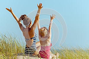 Modern mother and child in swimwear on ocean shore rejoicing