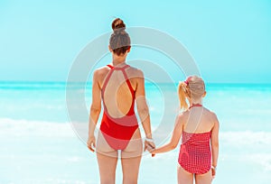 Modern mother and daughter standing on seacoast