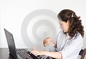 Modern mother holding baby while working in office