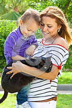 Modern mother holding her son and their black cat