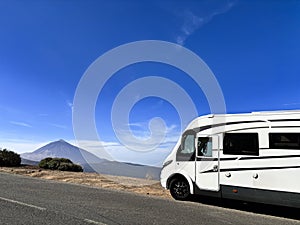 Modern motorhome camper van rv vehicle parking in the outdoors nature park with high mountain in background. Concept of travel and