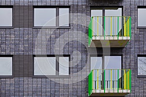 Modern multi-storey residential building with black facade finish and bright green and yellow balconies in Europe. Townhouse in a