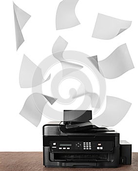 Modern multifunction printer on table and flying sheets of paper against white background